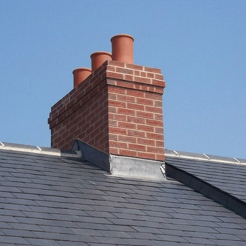 Brick chimney stack with three clay pots and lead apron flashing on a slate roof
